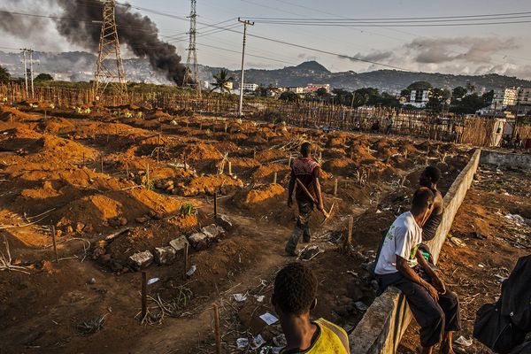 伊波拉疫情爆发期间，在狮子山自由城的汤姆王墓地工作一天后，挖掘工人停下工作休息。去年12月时，他们每天大约埋葬50具尸体，到​​了今年1